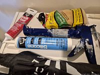 Sealant tubes, caulking gun, grout bag on shelf