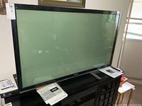 Front view of Panasonic 50" flat screen TV on base stand with manual and documents visible