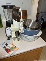 Wide view of Oster blender, immersion blender, nested bowls and dishes on counter