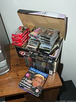 Box containing mixed cassettes, sealed blank tapes, DVDs and VHS