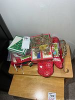 Stacked items on table including oven mitt, pot holders, star topper, cards, tray