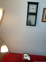 Wall clock on wall with angelfish ornament, red sofa below