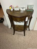 Front view of demi-lune table showing drawer, legs and lower shelf