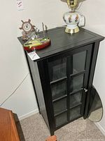 Front angled view of black display cabinet with glass door