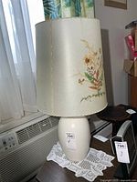 Full view of ceramic lamp with floral shade on table