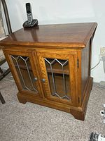 Front view showing wood cabinet, leaded glass doors, top surface