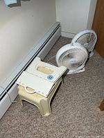 Two Airworks fans beside beige plastic step stool