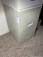 Front left view of metal two-drawer filing cabinet showing recessed pulls and lock