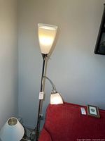 Full view of lamp next to couch showing both light heads illuminated