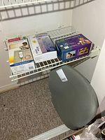 Shelf with three boxed therapeutic devices and gray back support cushion below