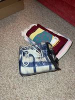 Stack showing electric blanket in zip case, wool throw and handmade rug