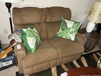 Front view of brown La-Z-Boy reclining loveseat with pillows and throw blanket