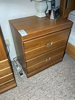 Left nightstand showing wood finish, two drawers, hardware