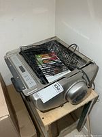 Top view of stainless steel rotisserie oven with basket, manual and power cord