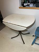 Table with both leaves lowered showing oval top and brown metal pedestal base