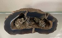Side view of agate geode displaying hollow interior with pyrite and miner figurines
