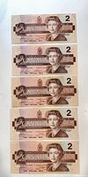 Stack of five Canadian $2 notes, obverse side showing portrait and denomination