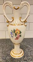 Front view showing entire vase, swan handles, floral design and gold trim