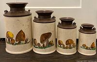 Front view of all four hand-painted stoneware milk-jug canisters