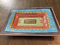 Top view of rectangular glazed pottery tray showing geometric folk art design