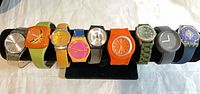 All twelve colourful watches displayed on black watch stand