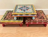 Three stacked hand-painted low tables front view
