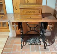 Full front view of oak sewing machine table on cast-iron base with wooden cover