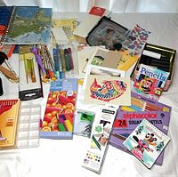 Overview of art supplies, pastels, pencils, pens, brushes, stickers and cards on table