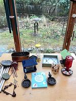 Overall lot view on tabletop showing feeders, birdhouses, planters, book and accessories