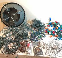 Overall lot with tree stand, multiple green-wire light strands, brown cord