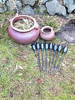 Two brown ceramic pots and eight solar lights displayed on grass in front of stone wall