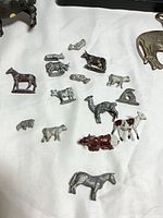 Group of small cast metal farm animal figurines on tabletop