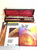 Flute in open red-lined case with two flute method books