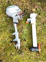 Honda outboard motor and separate mount laid on grass