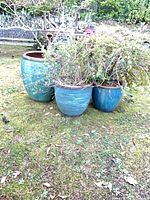 Three blue glazed ceramic pots grouped outdoors