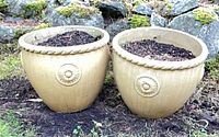 Front view of both beige ceramic planters with soil