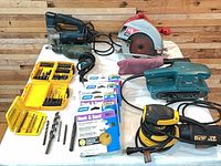 Group shot of all power tools, bit sets and sanding discs on table