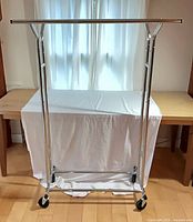 Front view of chrome rolling clothes rack on casters