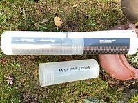 Rolled solar panel inside clear tube on ground