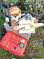 Chainsaw body, chain, manual, guide bar and fuel can on grass