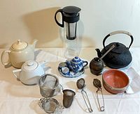 Group shot of all teapots, pitcher, bowls and strainers