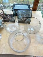 Tabletop view showing framed terrariums, three large glass bowls, small bottles