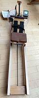Front view of Topiom wooden water rower showing seat, rails, footrests, tank, monitor