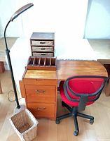 Full lot view showing file cabinet with fold-out desk, red chair, floor lamp, storage cube and wastebasket