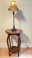 Full view of round wooden side table with lamp on top