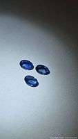 Three oval blue sapphires grouped on neutral background