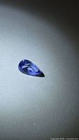 Pear-shaped blue tanzanite on neutral background