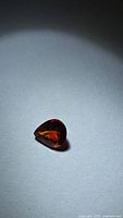 Pear-cut burnt orange spessartite garnet on neutral background