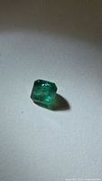 Loose square emerald-cut green gemstone on surface