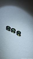 Three oval blue-green sapphires on light background